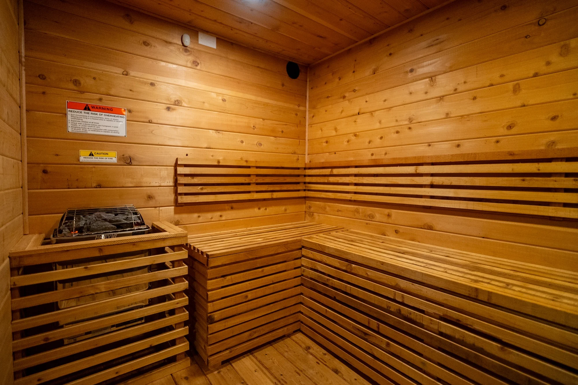 Interior of custom cedar sauna with L-shaped benches and Harvia heater