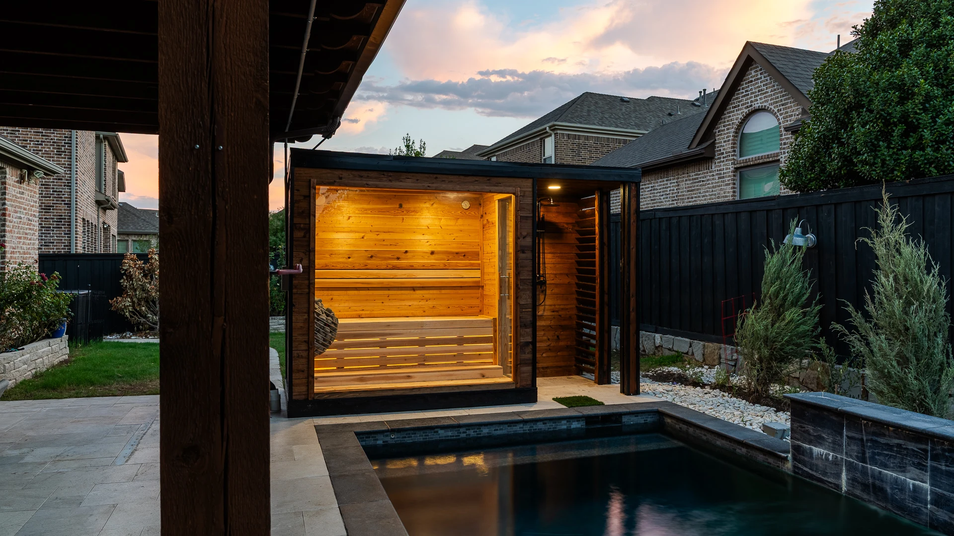Poolside sauna viewed from under the pergola with landscaping