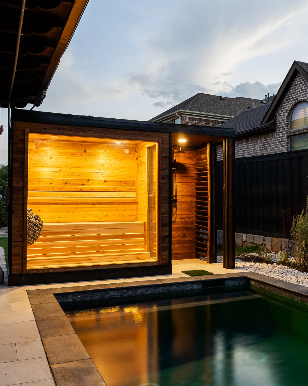 Sauna reflecting in the pool corner with white rock landscaping at dusk